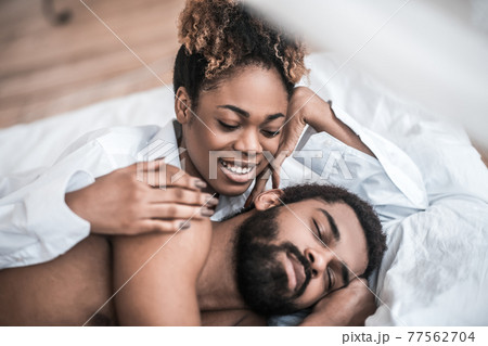 Happy woman touching sleeping man in bed 77562704