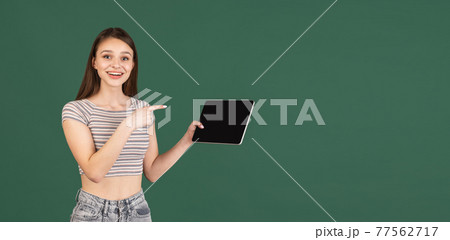 Young Caucasian woman using digital tablet isolated on green background. Young Caucasian woman using digital tablet isolated on green background. 77562717