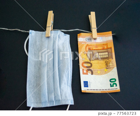 Euro banknote of 50 bill on a wooden peg and a rope and next to the mask on a clothespin. The concept of coronavirus and money. european union economic crisis concept. 77563723