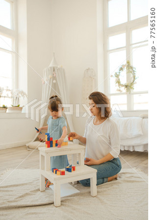 A young mother spends time with her little daughter at home. A young mother spends time with her little daughter at home. 77565160