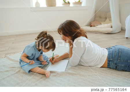 A young mother spends time with her little daughter at home. A young mother spends time with her little daughter at home. 77565164