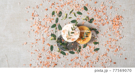 Three round natural handmade soaps and salt with the twigs of eucalyptus on the cotton background. Zero waste concept of bathing without any package and only with natural ingredients. Three round natural handmade soaps and salt with the twigs of eucalyptus on the cotton background. Zero waste concept of bathing without any package and only with natural ingredients. 77569070