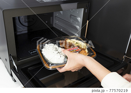 電子レンジでコンビニ弁当を温める女性の手元 77570219