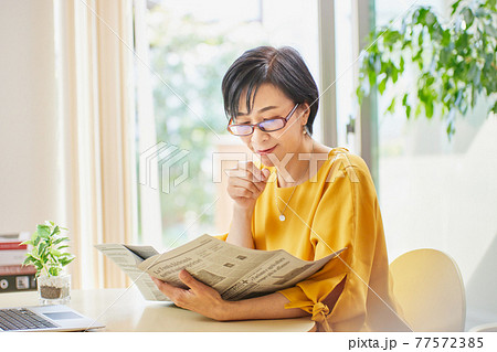 老眼鏡を掛けて英字新聞を読むミドル女性 老眼鏡を掛けて英字新聞を読むミドル女性 77572385