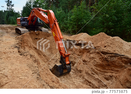 Excavator dig trench at forest area. Backgoe on earthwork for laying crude oil, natural gas pipeline 77573875