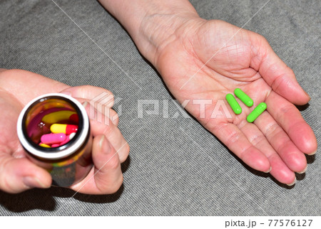 Pills in capsules in woomen hand. Medicine grade pharmaceutical tablets. Pills in capsules in woomen hand. Medicine grade pharmaceutical tablets. 77576127