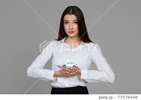 beautiful woman in shirt holding little white car beautiful woman in shirt holding little white car 77576448