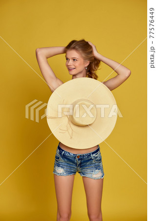 beautiful young blonde woman in shorts with straw hat 77576449
