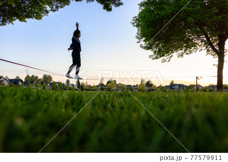 Adventurous White Caucasian Adult Woman walking on a Slackline 77579911