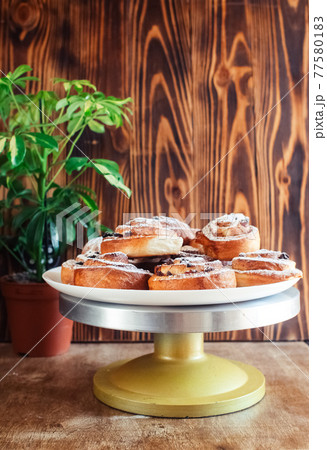 Puff pastry cakes curl with powdered sugar on top. A close-up of a bakery product. Confectionery work and customer service. A treat on a tray. 77580183