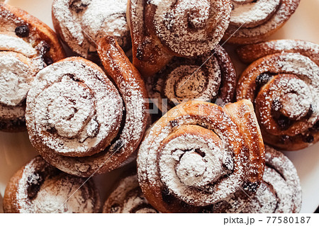 Puff pastry cakes curl with powdered sugar on top. A close-up of a bakery product. Confectionery work and customer service. A treat on a tray. 77580187