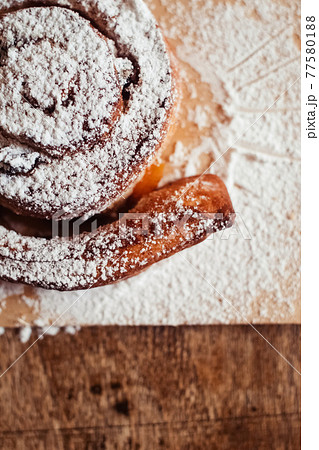 Puff pastry cakes curl with powdered sugar on top. A close-up of a bakery product. Confectionery work and customer service. A treat on a tray. 77580188