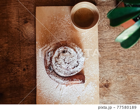Puff pastry cakes curl with powdered sugar on top. A close-up of a bakery product. Confectionery work and customer service. A treat on a tray. 77580189