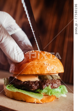 Mini burger on a stand close-up. Children fast food in a restaurant or cafe. Macro photo of burger ingredients with meat and vegetables. Eco burgers for children Mini burger on a stand close-up. Children fast food in a restaurant or cafe. Macro photo of burger ingredients with meat and vegetables. Eco burgers for children 77580196