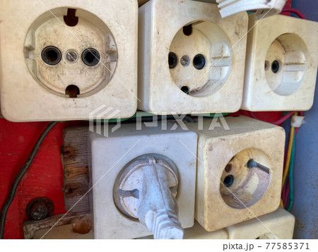 Large white unprofessionally installed many square electrical outlets in an electrical panel 77585371