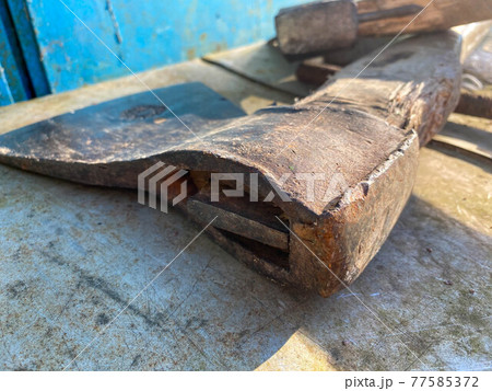 An old iron metal ax with a butt and a rusty and texture beautiful handle for chopping firewood, wood and trees lies on an iron background An old iron metal ax with a butt and a rusty and texture beautiful handle for chopping firewood, wood and trees lies on an iron background 77585372