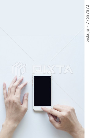 スマートフォンを操作する女性の手 白バック スマートフォンを操作する女性の手 白バック 77587872
