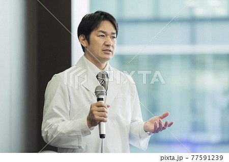 マイクを持って話す白衣の男性 医師 研究者 マイクを持って話す白衣の男性 医師 研究者 77591239