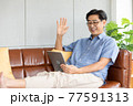 senior asian man say hi and talking with his family/friends via digital tablet 77591313