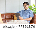 senior asian man using digital tablet on sofa 77591370