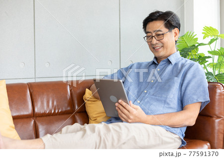 senior asian man using digital tablet on sofa 77591370