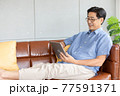 senior asian man using digital tablet on sofa 77591371