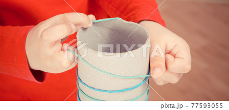 Little boy putting rubber bands or erasers on cardboard roll 77593055
