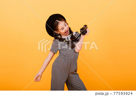 Portrait of baby girl holding photo camera isolated on yellow background 77593924