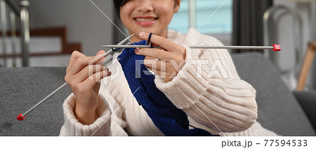 Cropped shot of happy girl knitting while sitting on couch in living room. Cropped shot of happy girl knitting while sitting on couch in living room. 77594533