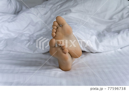 Morning and waking up. Feet under the covers in bed in the morning. Women's feet under the covers in a white bed. Relax, sleep, rest concept. Morning and waking up. Feet under the covers in bed in the morning. Women's feet under the covers in a white bed. Relax, sleep, rest concept. 77596738