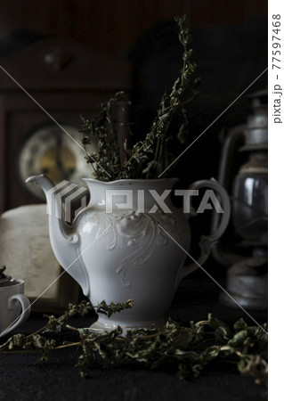 Tea Party. Cup of tea and Teapot on wooden table with old clock and book in Background Tea Party. Cup of tea and Teapot on wooden table with old clock and book in Background 77597468
