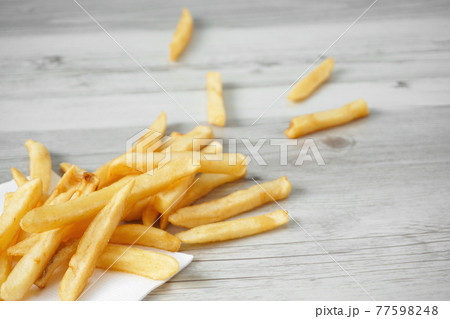 テーブルの上に散らばったフライドポテトのクローズアップ テーブルの上に散らばったフライドポテトのクローズアップ 77598248