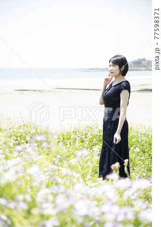 海を眺める若い女性と花畑 神奈川県鎌倉市由比ガ浜 の写真素材