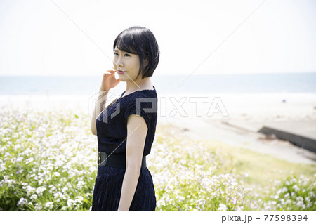 海を眺める若い女性と花畑 神奈川県鎌倉市由比ガ浜 の写真素材