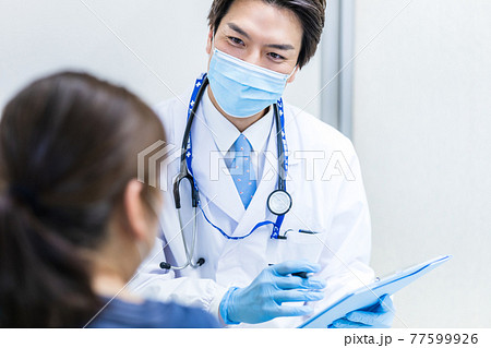 コロナウイルスワクチン予防接種の問診をする医師 77599926