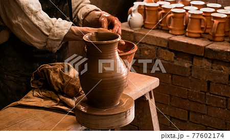 Potter hands making in clay on pottery wheel. Authentic pottery workshop 77602174