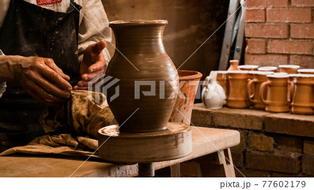 Potter hands making in clay on pottery wheel. Authentic pottery workshop Potter hands making in clay on pottery wheel. Authentic pottery workshop 77602179