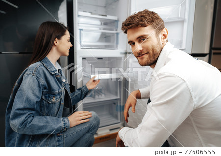 Young couple selecting new refrigerator in household appliance store Young couple selecting new refrigerator in household appliance store 77606555