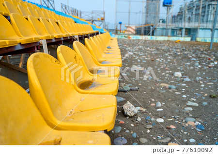 Yellow plastic seats on the podium of a small sports field Yellow plastic seats on the podium of a small sports field 77610092
