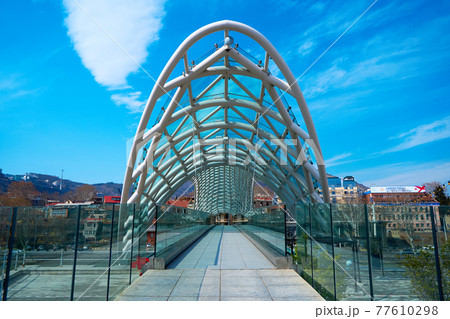 Modern stylish design made of glass and metal, pedestrian bridge over the Kura river in Tbilisi Modern stylish design made of glass and metal, pedestrian bridge over the Kura river in Tbilisi 77610298