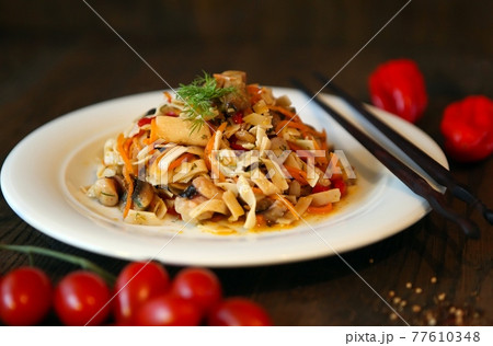 Noodles salad with shrimps on a white plate and sticks. Spicy Korean-style salad on a wooden table. Noodles salad with shrimps on a white plate and sticks. Spicy Korean-style salad on a wooden table. 77610348