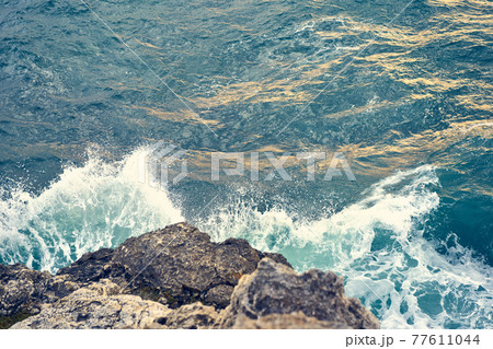 Splashes from the waves bumping against the rocky shore 77611044