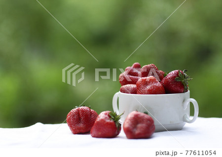 strawberry in bowl close up vertical photo with copy space on green grass background 77611054