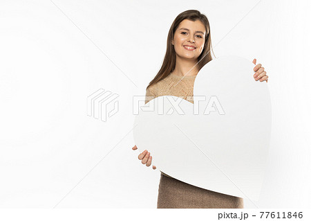 Girl with a large white heart shape in the hands. A student in love stands and holds a large heart shape in her hands. Valentine's Day and love. Girl with a large white heart shape in the hands. A student in love stands and holds a large heart shape in her hands. Valentine's Day and love. 77611846