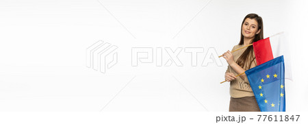 Young girl with the flag of the European Union and Poland. The student is holding two flags in her hand. Woman with flags on white background. Panoramic frame. 77611847