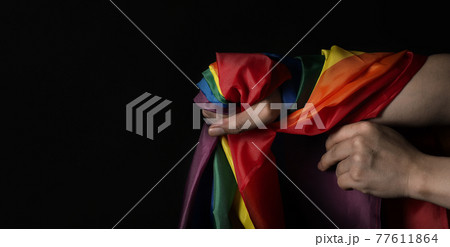 LGBTQ pride flag. Lesbian Gay Bi sexsual Transgender Queer. Homosexsual pride Rainbow flag in gay hand. black background. Represent symbol of freedom, peace, equality and love. LGBTQ concept. 77611864