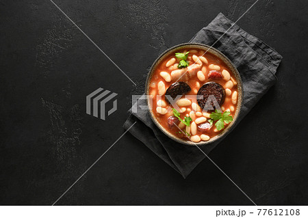 Spanish asturiana fabada with chorizo and morcilla on black background. 77612108