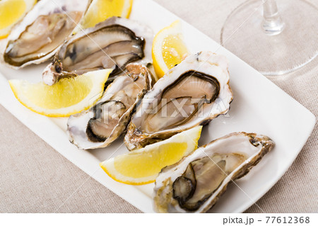 Tasty oysters with lemon on plate top view 77612368
