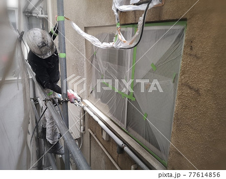 モルタル外壁へ吹き付け塗装をおこなう男性塗装職人下向き モルタル外壁へ吹き付け塗装をおこなう男性塗装職人下向き 77614856