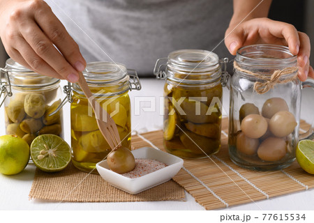Homemade various pickled fruit in a glass jar with hand Homemade various pickled fruit in a glass jar with hand 77615534